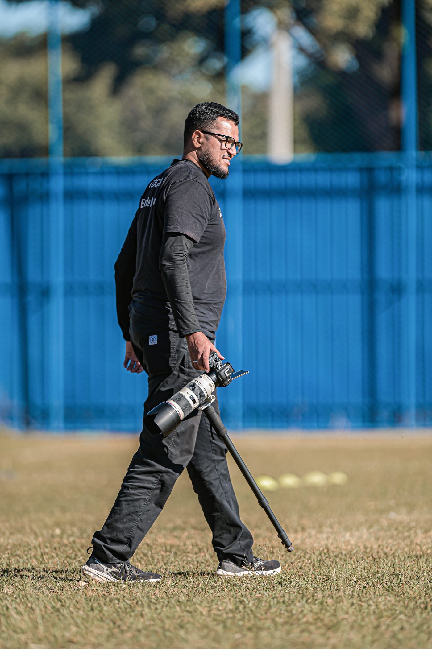 Fotógrafo de evento caminhando pelo campo com a câmera na mão